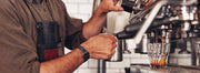 A barista frothing milk with a commercial espresso machine.