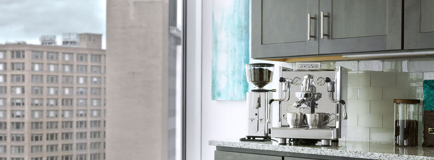 A coffee and espresso grinder sitting on a white counter next to a large window overlooking the city.
