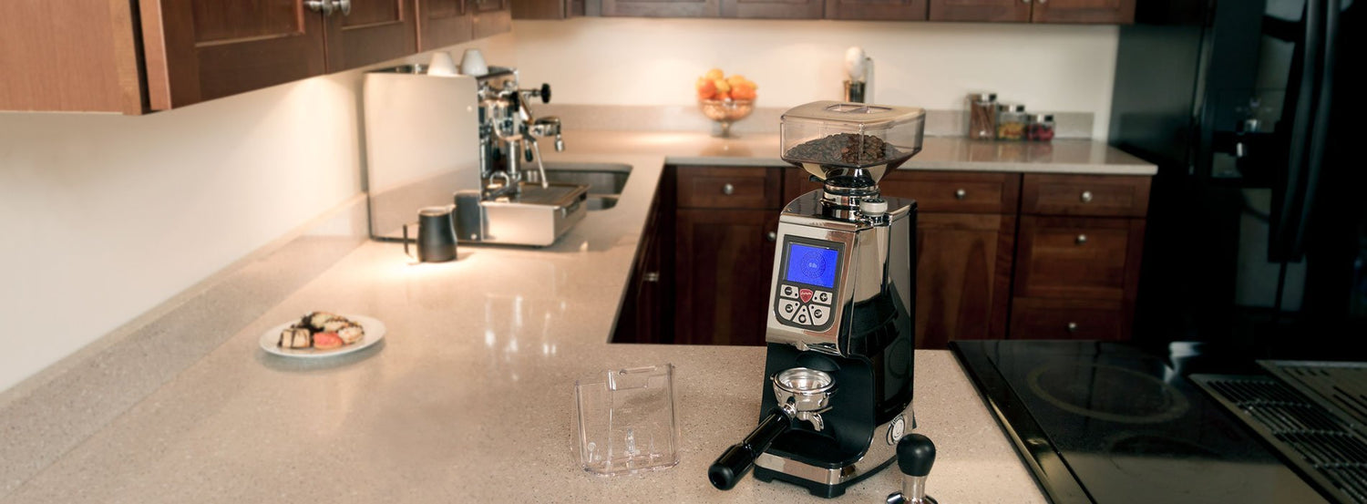A coffee grinder resting on the corner of a warmly lit marble countertop.
