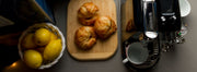 Overhead look at a single serve espresso machine next to croissants and lemons.