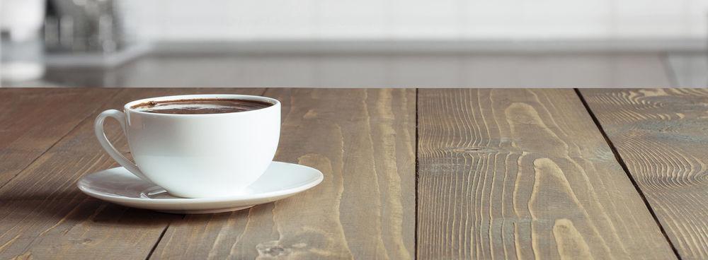 A Konitz Porzellan cup and saucer on a wood table.