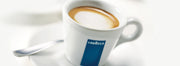 Espresso in a white espresso cup with a blue stripe and Lavazza logo