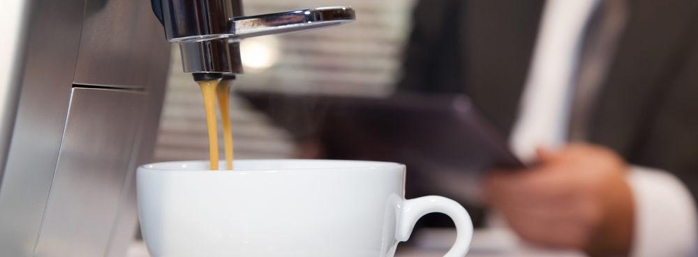 A Saeco automatic espresso machine brewing espresso into a white coffee cup.
