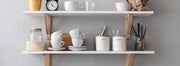 Two white shelves on a white wall, holding a collection of Barista Basics items.