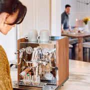 ECM Synchronika II with Walnut accents espresso machine with cups on a counter in a kitchen setting