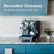 Black ECM Mechanika MAX Espresso machine on a kitchen counter with blue cabinets and a December Giveaway text overlay.