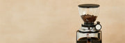 Ceado E37S coffee grinder with coffee beans in the hopper on a beige background