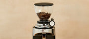 Close-up of a Ceado E37S coffee grinder with coffee beans in the hopper on a beige background
