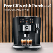 JURA J8 Twin in Diamond Black with two glasses of coffee on a wooden background, promoting free gifts with purchase.