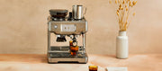 Close-up of the Breville Barista Touch Espresso machine on a wooden surface with a neutral background.