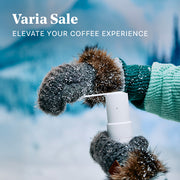 Person wearing winter gloves using a Varia EVO Hand Grinder in a winter snow setting promoting a Varia Sale.