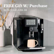 JURA S8 machine with a cup on a white countertop in a kitchen setting with promotional text overlayed that reads "FREE Gift with Purchase".