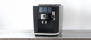 Close-up of a JURA J10 Twin in black on a gray and black counter top in front of a white wall.