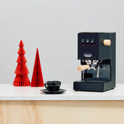 Thunder Black Gaggia semi-automatic machine with Tiger Maple accents on a white countertop with red decorative trees and a black cup.